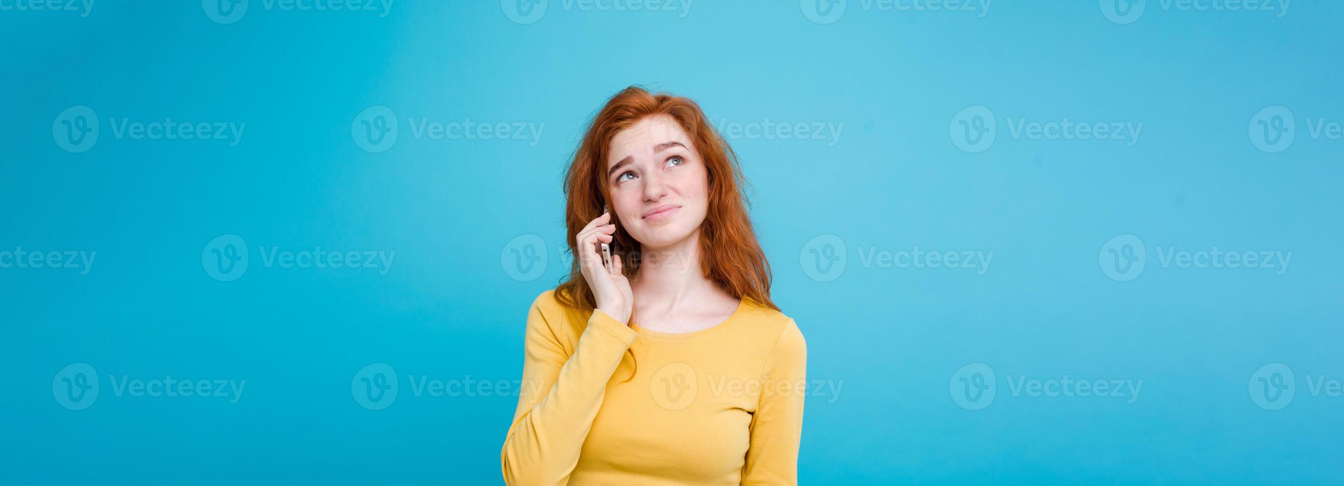 Lifestyle concept - Portrait of ginger red hair girl with shocking and stressful expression while talking with friend by mobile phone. Isolated on Blue Pastel Background. Copy space photo