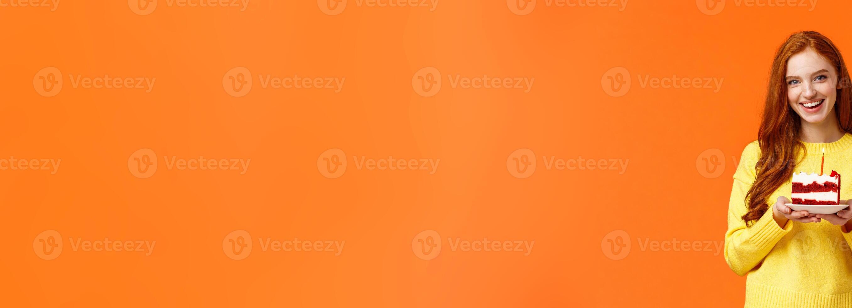 Girlfriend made surprise party, bring piece of cake with one candle to celebrate partner birthday, singing happy b-day and smiling lovely, standing orange background in yellow sweater photo