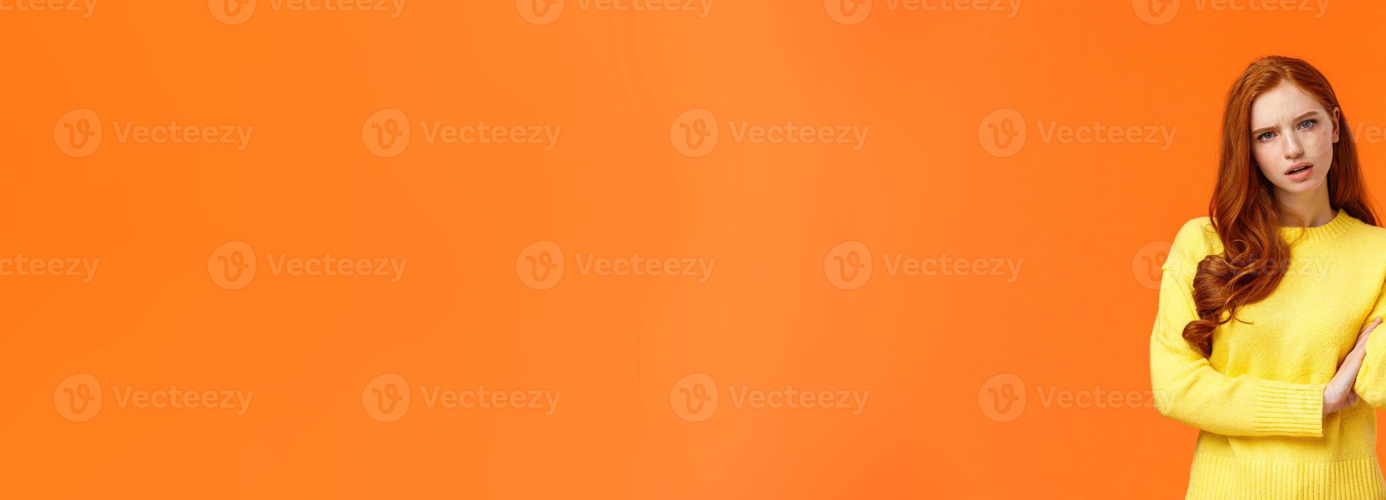 Skeptical and troubled, uncertain young redhead woman cant understand how resolve proble, shrugging raise hands sideways, frowning confused or unsure, standing frustrated orange background photo