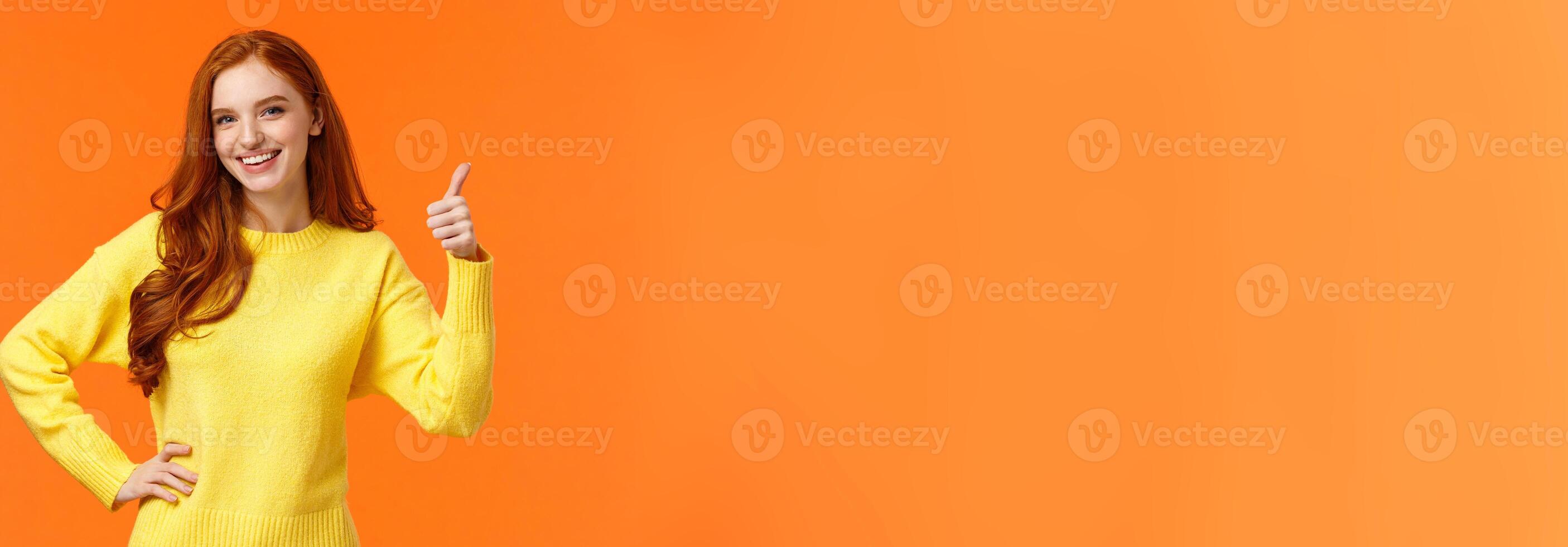 Sounds good, count me in. Waist-up shot cheerful upbeat girl make thumb-up gesture and smiling in approval, like idea, recommend consumer nice product, standing orange background photo
