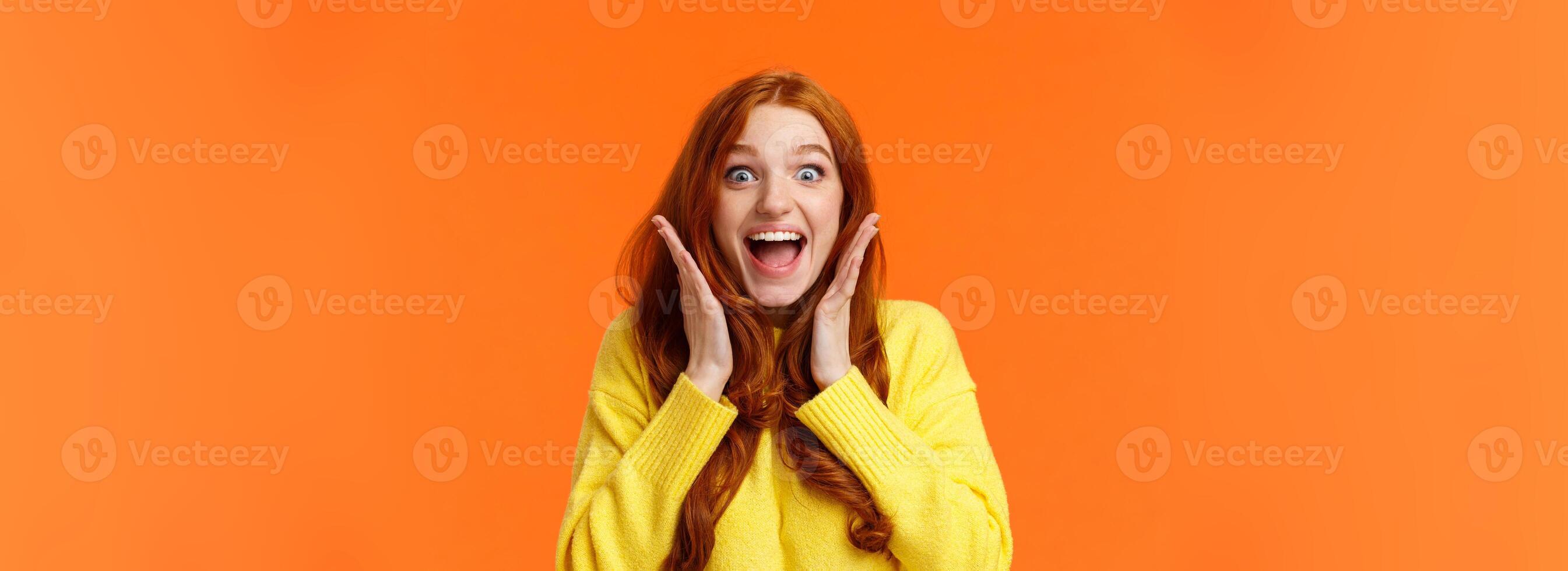 Excitement, emotions and holidays concept. Waist-up shot cheerful impressed and excited redhead woman screaming from thrill and joy, hold hands near face, open mouth and glance amazed photo
