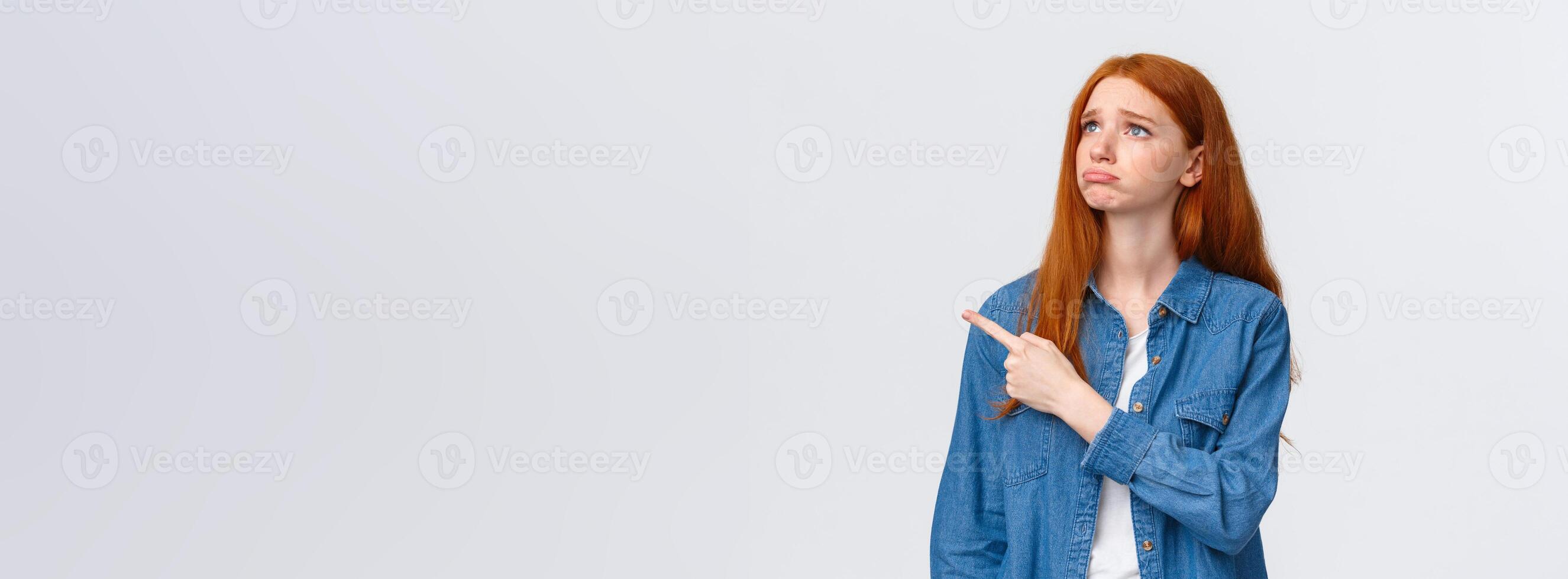 So pity. Upset gloomy cute redhead female student lost her chance participate exchange program, sobbing and looking grumpy pointing upper left corner, express regret and disappointment photo
