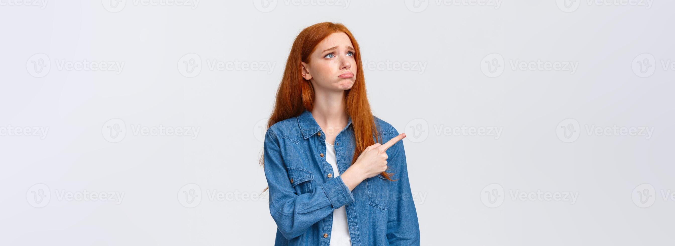 So pity. Upset gloomy cute redhead female student lost her chance participate exchange program, sobbing and looking grumpy pointing upper left corner, express regret and disappointment photo