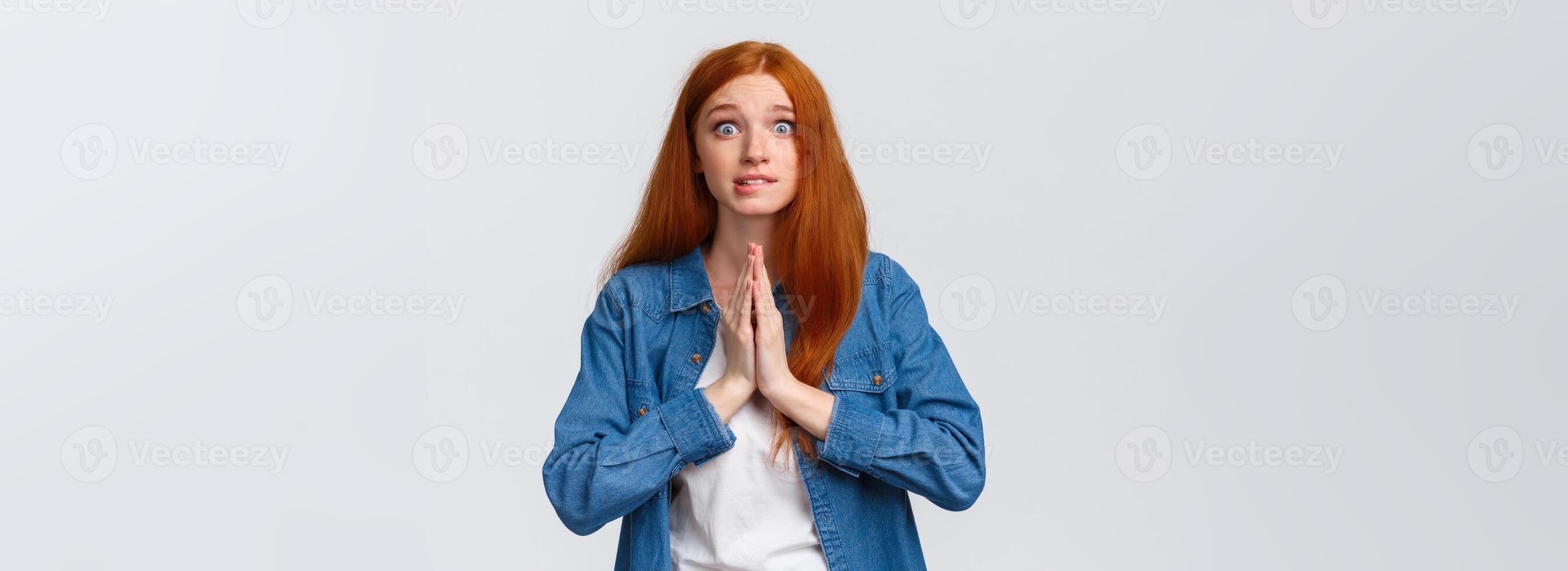 Waist-up portrait nervous redhead female student need help asap, hold hands over chest together in pray, smiling worried and impatient stare camera, pleading, begging favour photo
