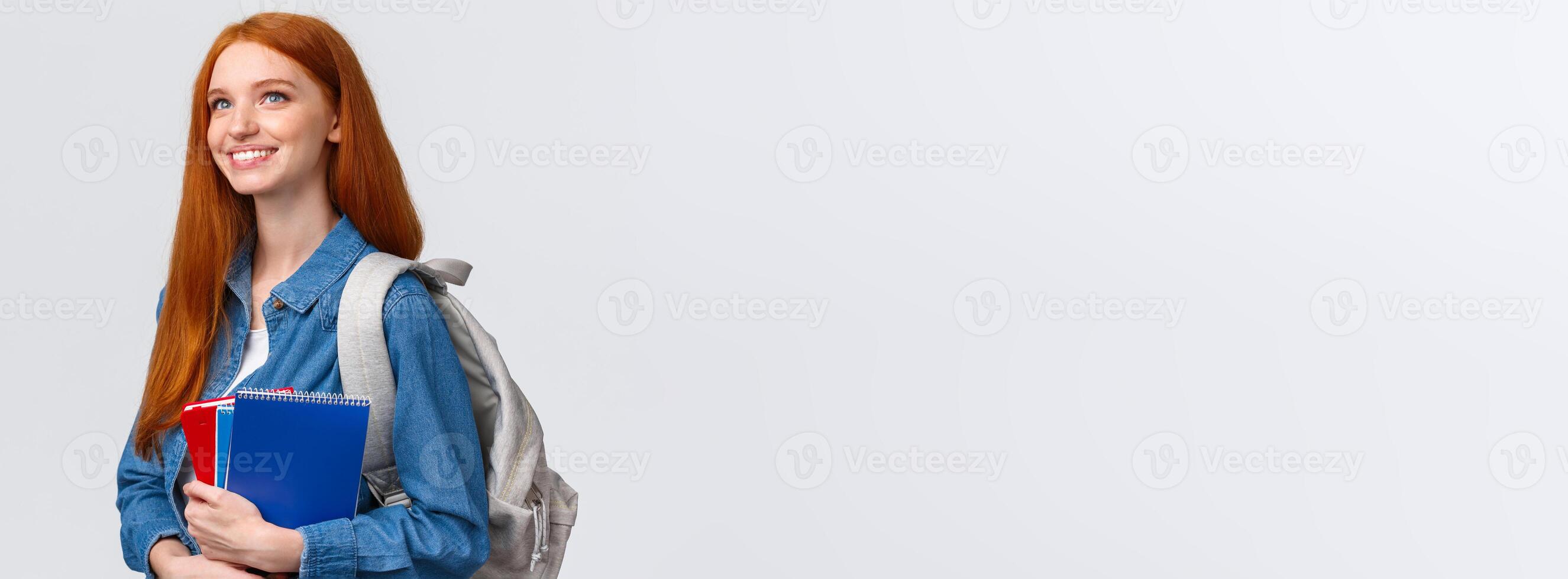 Youth, teenagers and education concept. Determined good-looking dreamy and upbeat smiling redhead female student with notebooks and backpack looking forward new theme in class photo