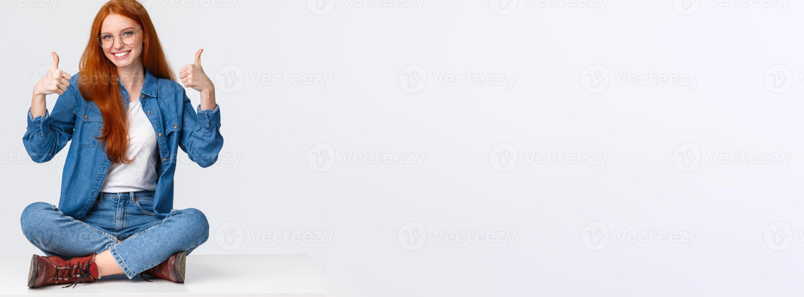 Excellent, satisfaction and people concept. Delighted supportive cute redhead girlfriend sitting on floor, with legs crossed in relaxed pose, smiling approval, showing thumbs-up cheering photo