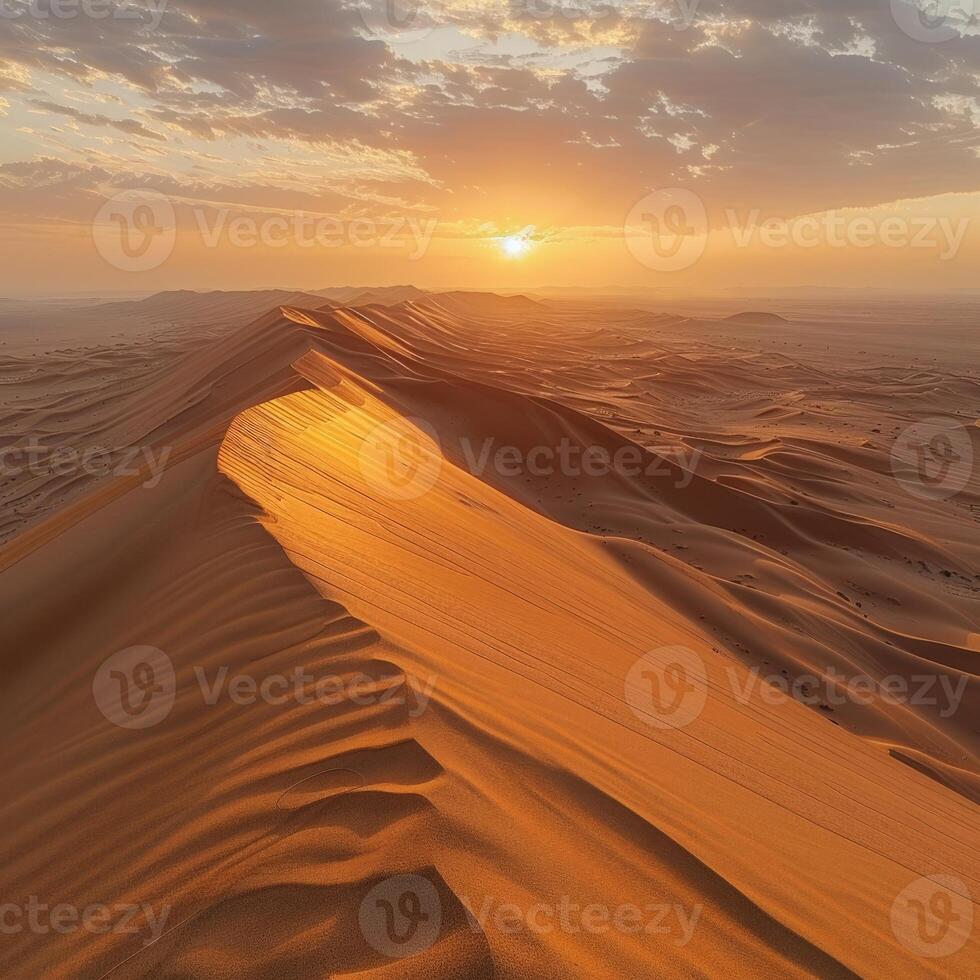 Sun casting warm glow on sandy dune in desert as it sets photo