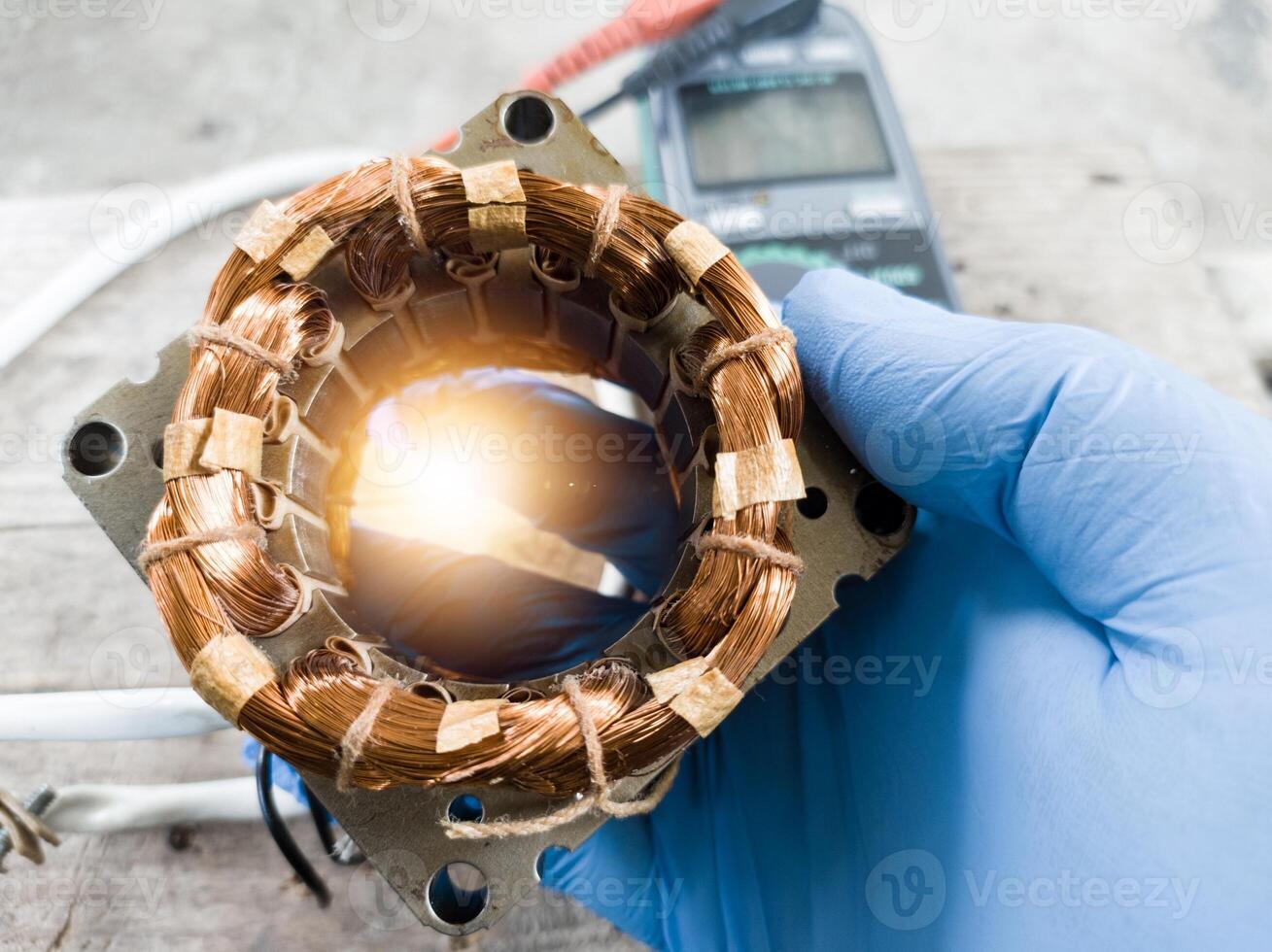 fan winding repair by a technician using blue gloves, fan motor winding repair concept. photo