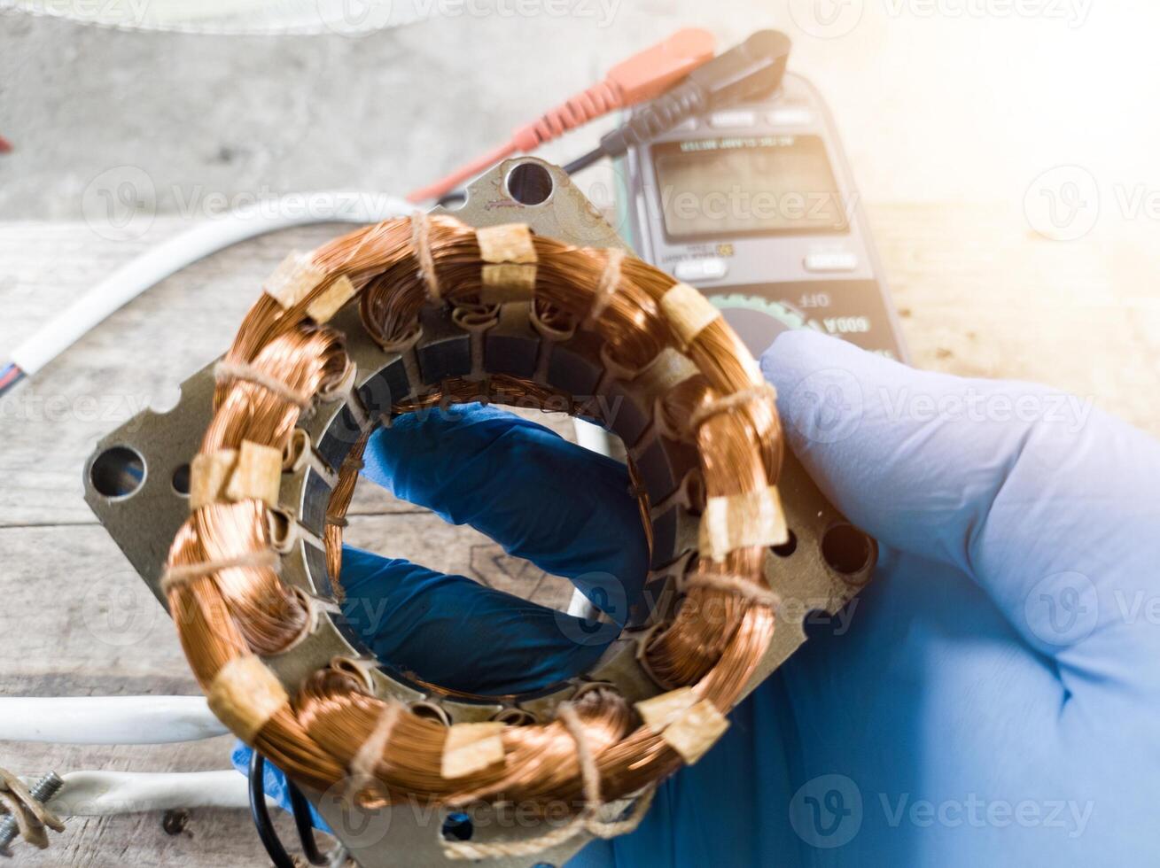 fan winding repair by a technician using blue gloves, fan motor winding repair concept. photo
