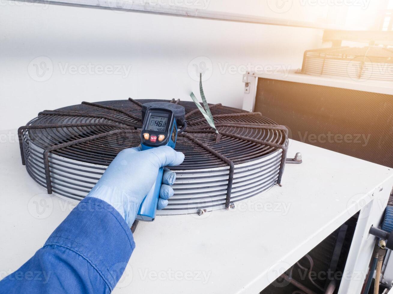 Measuring and checking the temperature of the condenser ventilation using a temperature gun by an engineer photo