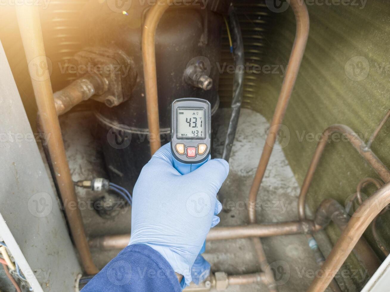 Professional engineer wearing blue gloves using thermo gun for temperature check on the hvac air cinditioning syatem. Temperature check concept on the compressor, condensor , refrigerant system hvac. photo