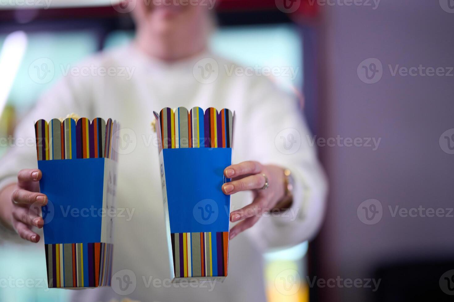 A vendor stands outside the cinema, holding freshly popped popcorn to sell to moviegoers before they enter the theater photo