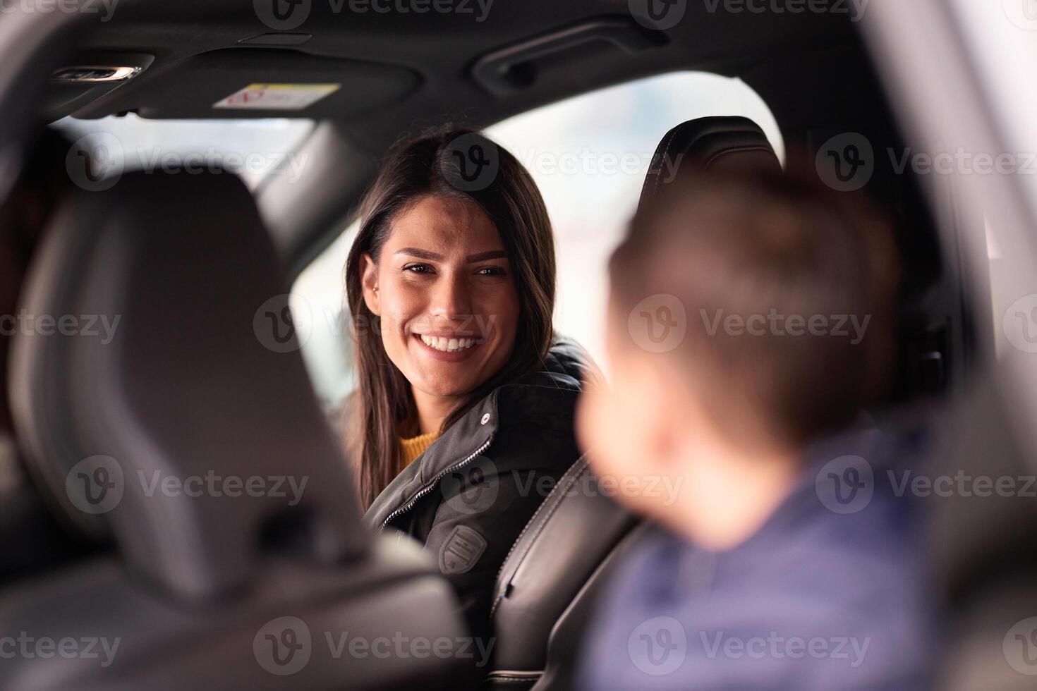 In the nighttime hours, a happy family enjoys playful moments together inside a car as they journey on a nocturnal road trip, illuminated by the glow of headlights and filled with laughter and joy photo