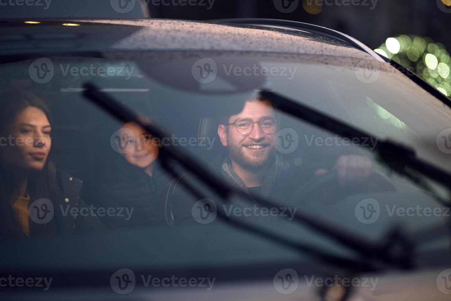 In the nighttime hours, a happy family enjoys playful moments together inside a car as they journey on a nocturnal road trip, illuminated by the glow of headlights and filled with laughter and joy photo