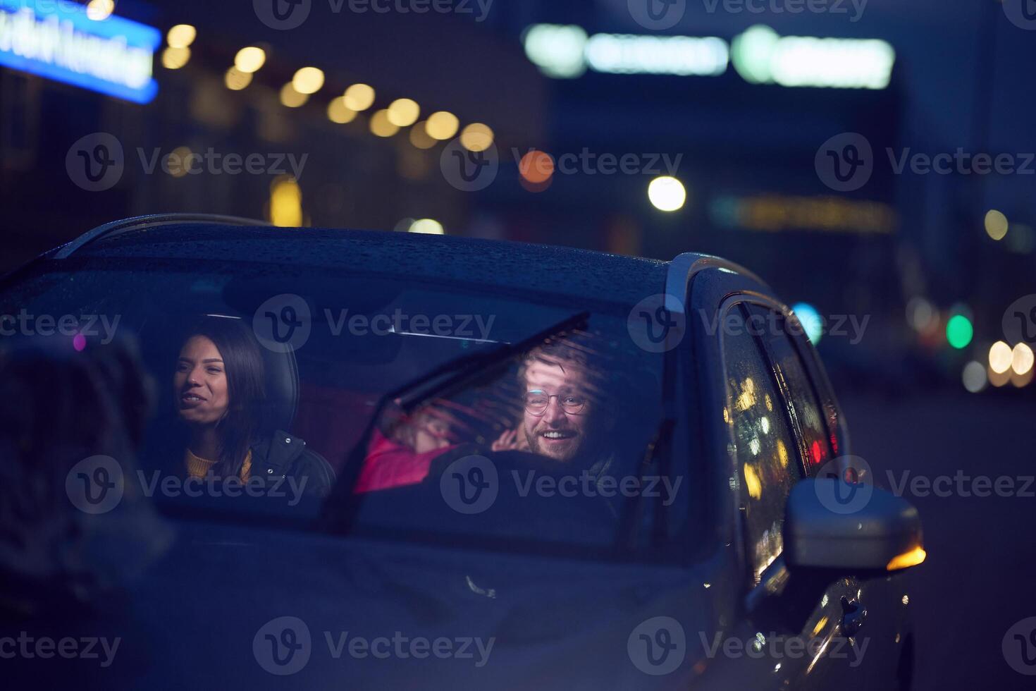 In the nighttime hours, a happy family enjoys playful moments together inside a car as they journey on a nocturnal road trip, illuminated by the glow of headlights and filled with laughter and joy photo