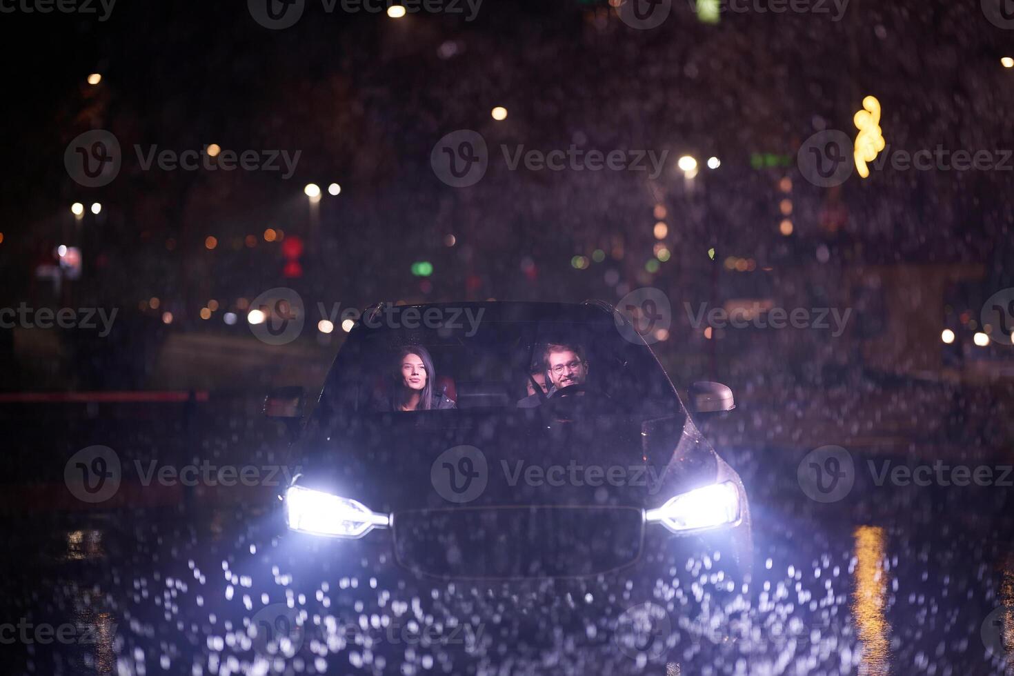 In the midst of a nighttime journey, a happy family enjoys playful moments inside a car as they travel through rainy weather, illuminated by the glow of headlights, laughter, and bonding photo