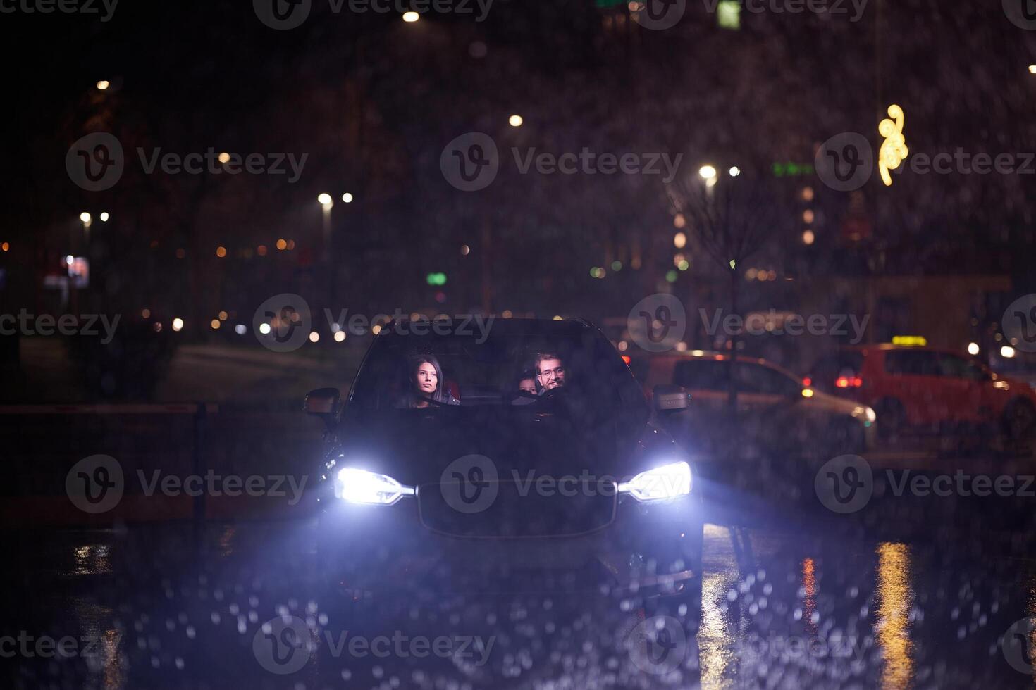 In the midst of a nighttime journey, a happy family enjoys playful moments inside a car as they travel through rainy weather, illuminated by the glow of headlights, laughter, and bonding photo