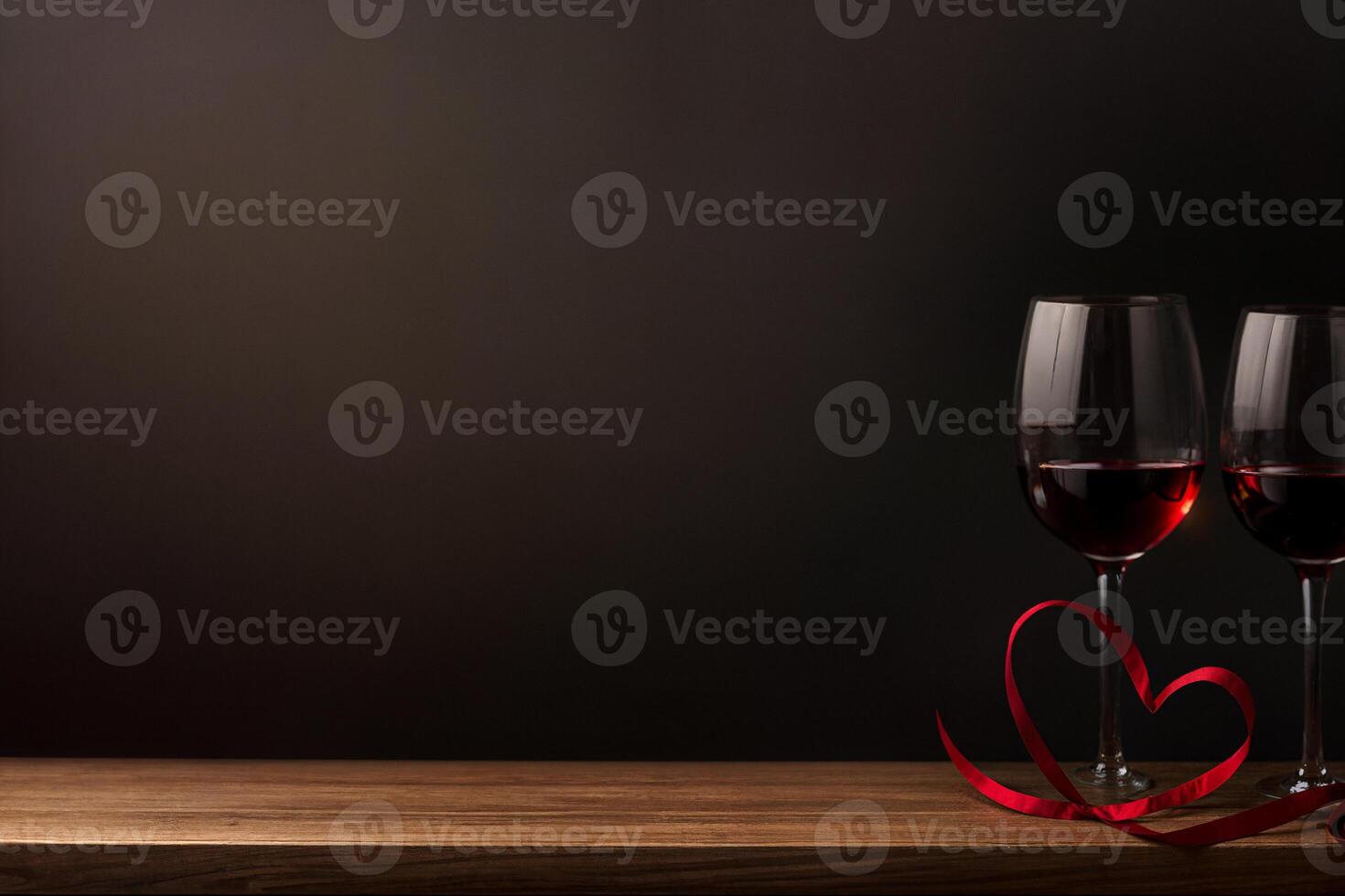 valentine's day, two glasses of champagne, red heart ribbon on a wooden table with space for text on a dark background photo