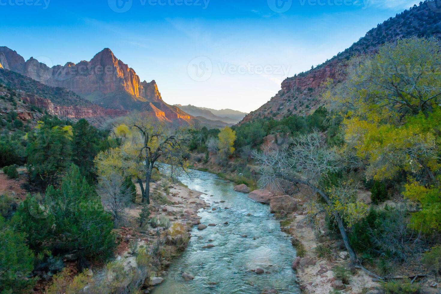 View of the Watchman in Zion National Park, Utah with Virgin River flowing to the mountain range during sunset, coloring the rocks orange photo