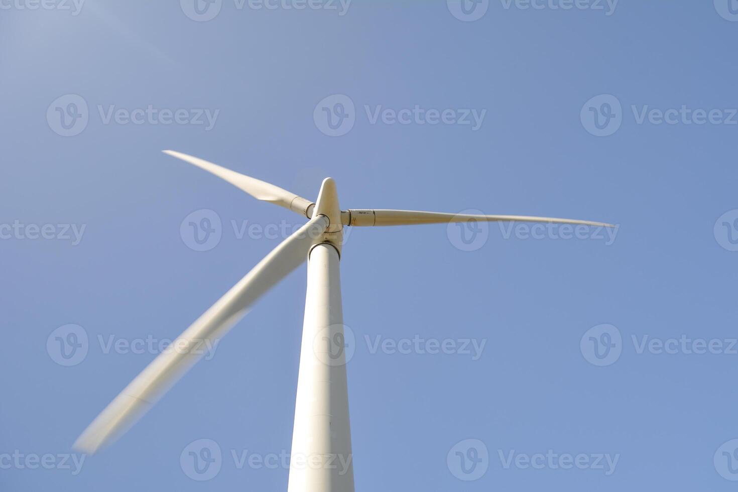 Close-up and low angle view of spinning blades of a wind turbine generating renewable energy photo