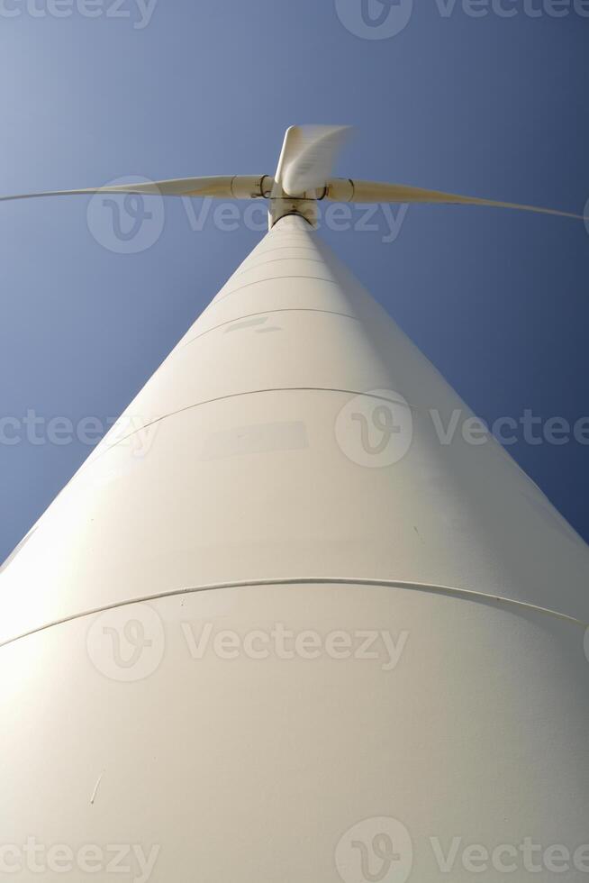 Close-up and low angle view of spinning blades of a wind turbine generating renewable energy photo