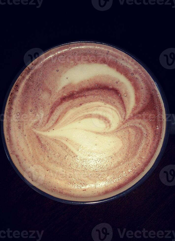 Directly above shot of cup of coffee with latte art on dark background. photo