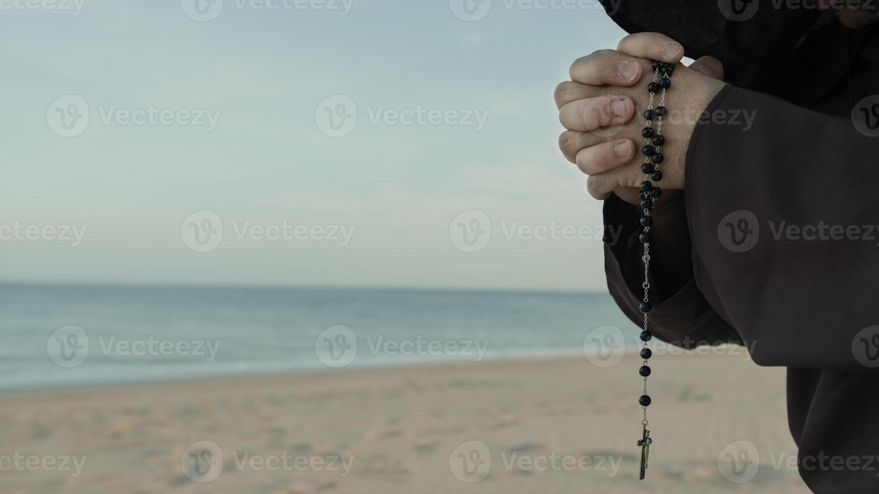 Religious Hands Of A Monk Praying Rosary On The Beach photo