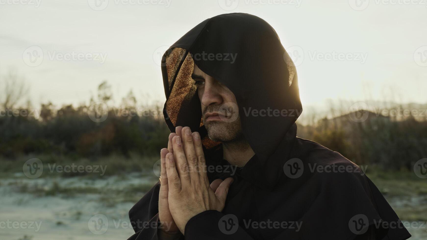 Religious Monk Wears His Hood And Prays In Nature At Sunset photo