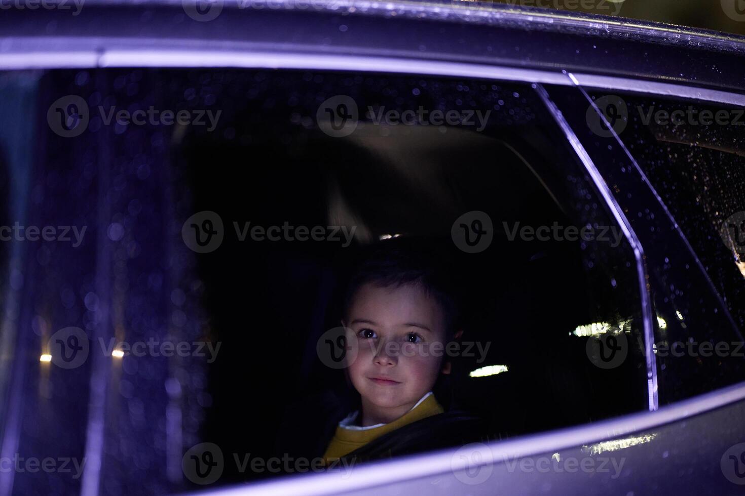 A young boy enjoys a car ride, captured through the window, as he observes the passing scenery. photo