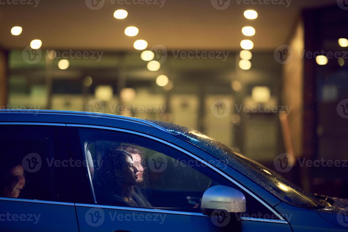 In the nighttime hours, a happy family enjoys playful moments together inside a car as they journey on a nocturnal road trip, illuminated by the glow of headlights and filled with laughter and joy photo