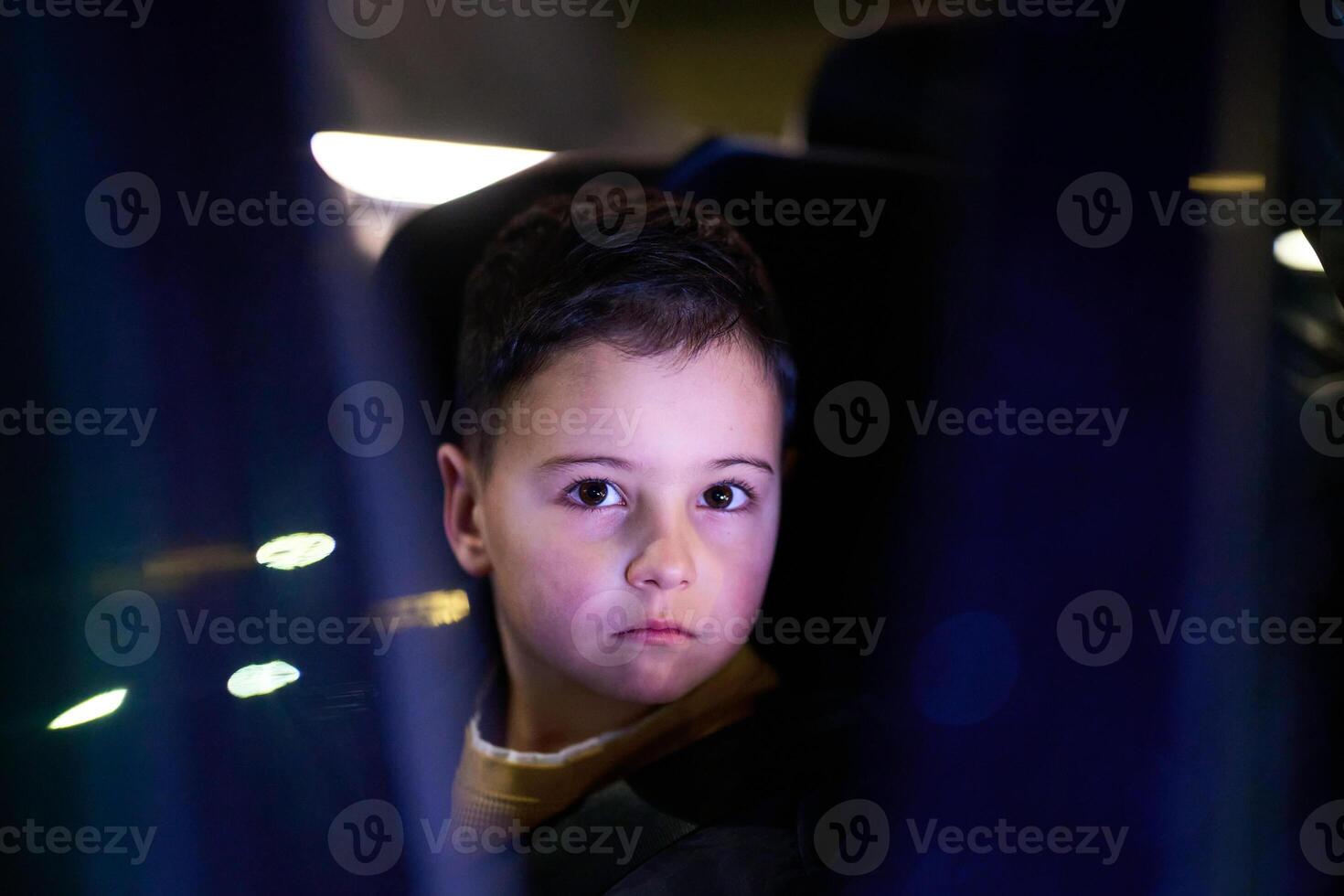 A young boy enjoys a car ride, captured through the window, as he observes the passing scenery. photo