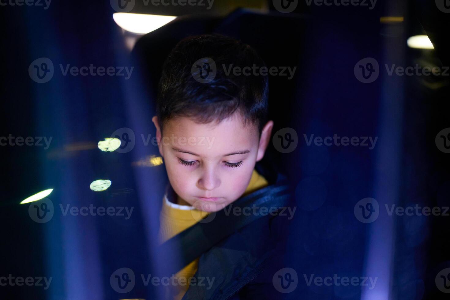 A young boy enjoys a car ride, captured through the window, as he observes the passing scenery. photo