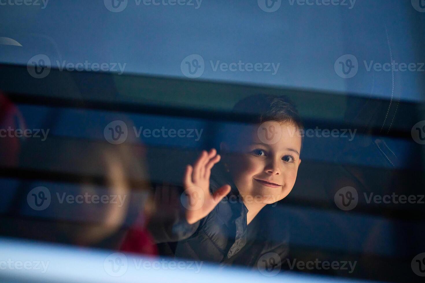 A young boy enjoys a car ride, captured through the window, as he observes the passing scenery. photo