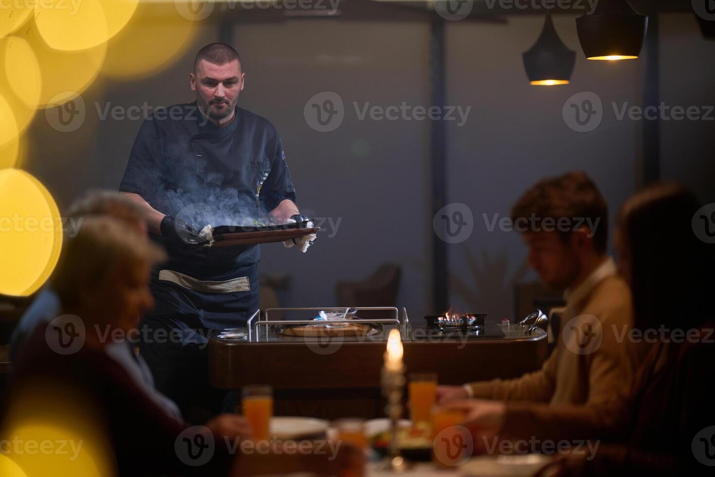In a restaurant setting, a professional chef presents a sizzling steak cooked over an open flame, while an European Muslim family eagerly awaits their iftar meal during the holy month of Ramadan photo