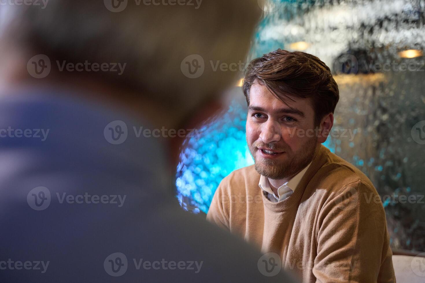 A son and his elderly father engage in heartfelt conversation while patiently awaiting their iftar meal, fostering intergenerational bonding and cherished moments of family connection photo