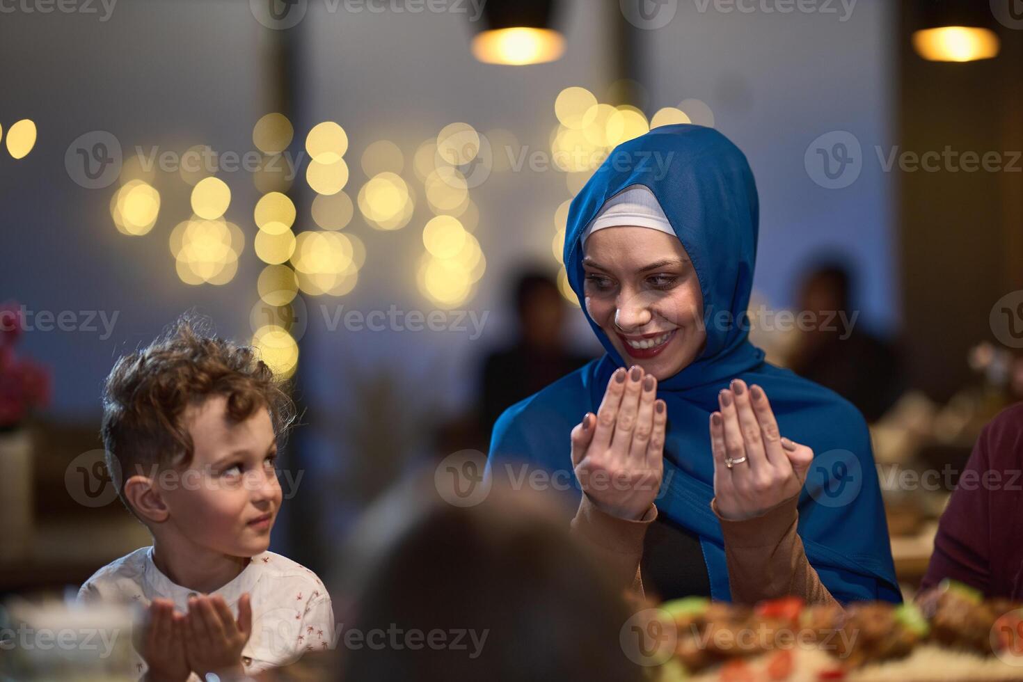 In a modern restaurant setting, a European Islamic family comes together for iftar during Ramadan, engaging in prayer before the meal, uniting tradition and contemporary practices in a celebration of photo