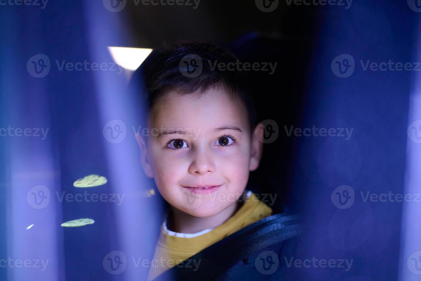 A young boy enjoys a car ride, captured through the window, as he observes the passing scenery. photo