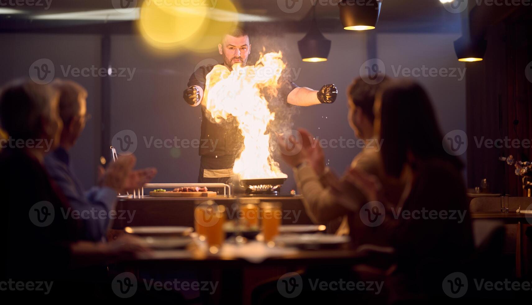 In a restaurant setting, a professional chef presents a sizzling steak cooked over an open flame, while an European Muslim family eagerly awaits their iftar meal during the holy month of Ramadan photo