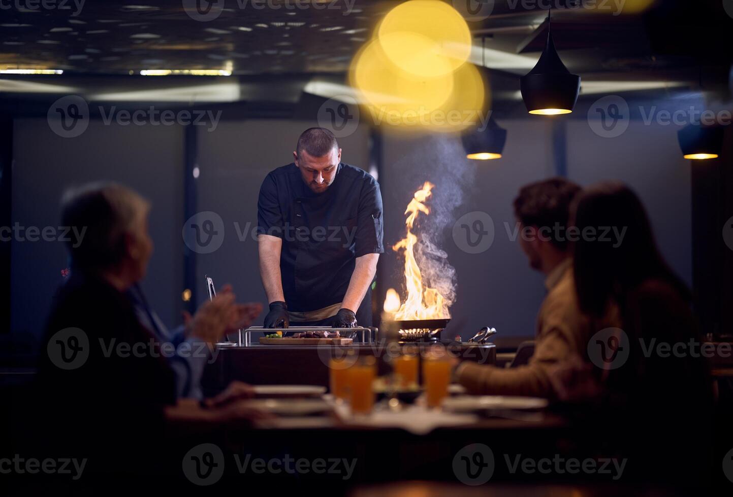 In a restaurant setting, a professional chef presents a sizzling steak cooked over an open flame, while an European Muslim family eagerly awaits their iftar meal during the holy month of Ramadan photo