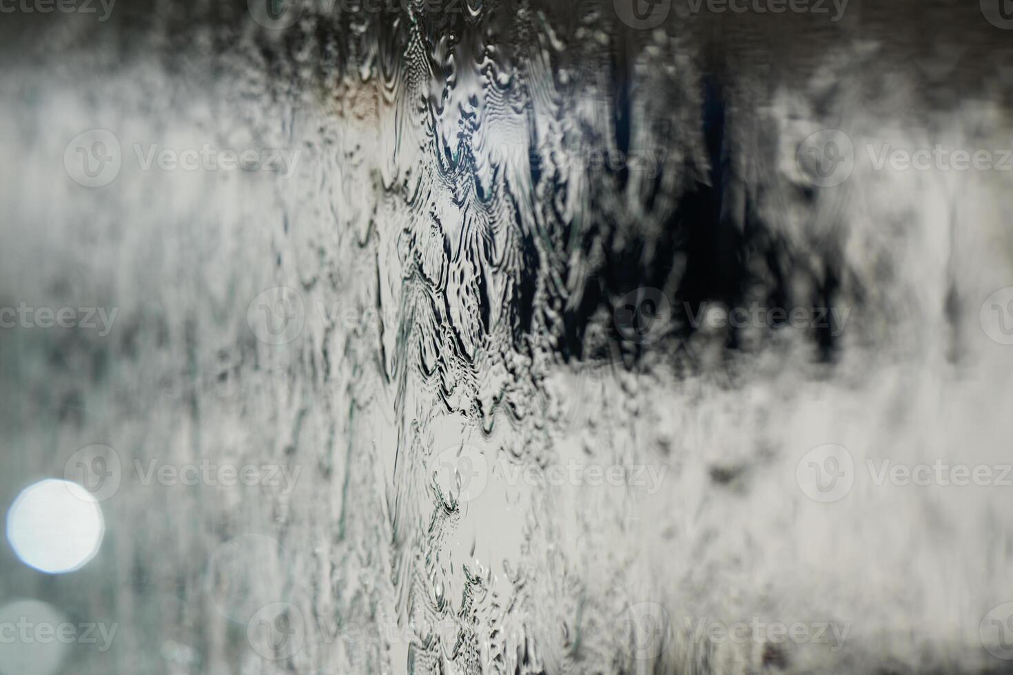 In a close-up capture, the texture of glass through which water flows is beautifully depicted, showcasing intricate patterns and the fluidity of movement in a mesmerizing display photo