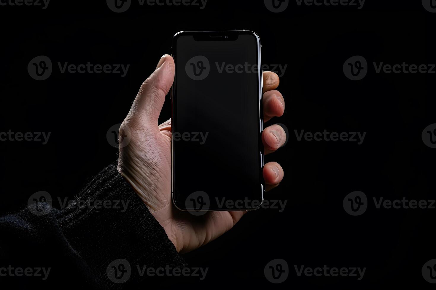 Someone holding a black cell phone in their hand against a black background photo