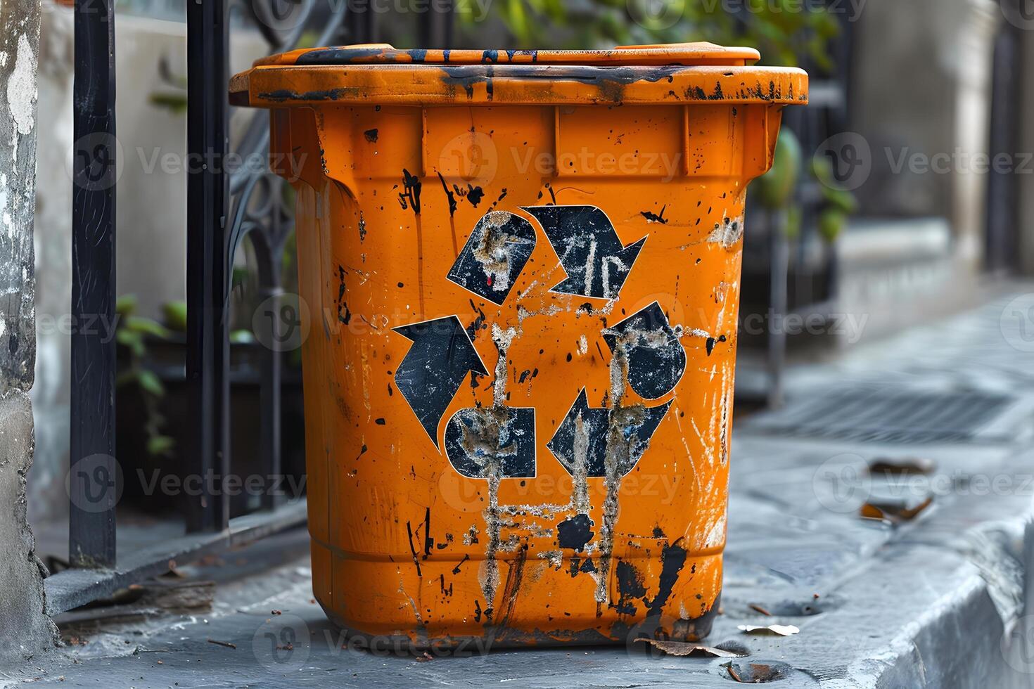 A trash can on sidewalk by fence photo
