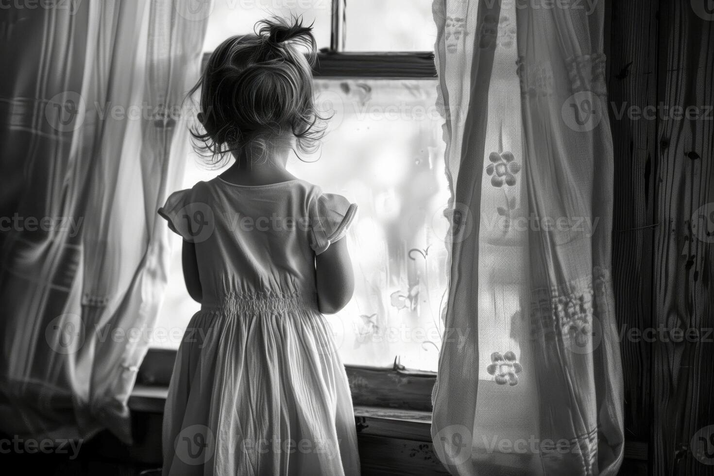Little girl peering through the window at the outdoors photo
