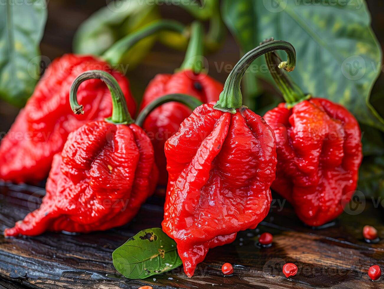 Red trinidad scorpion peppers on wooden board with leaves photo