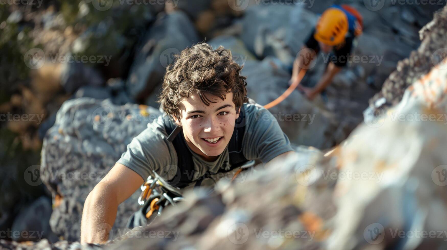 Teen Boy Rock Climbing with Safety Gear in Mountainous Terrain. Smiling and Enjoying Outdoor Adventure photo