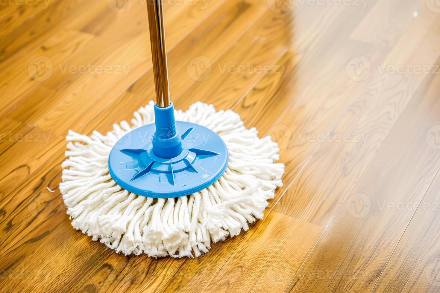 A close up of a mop on a wooden floor with a blue handle photo