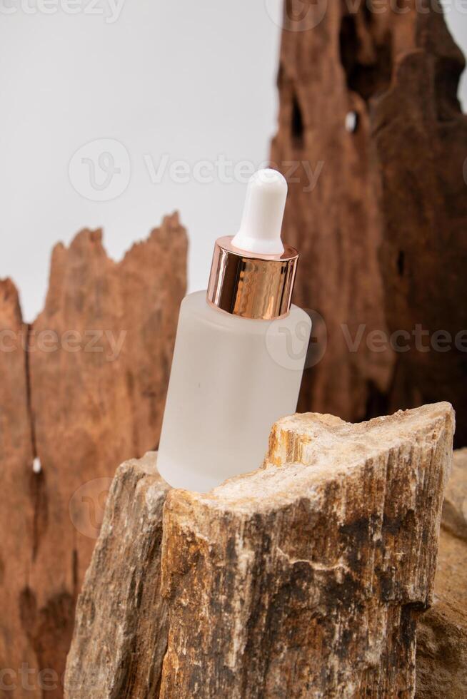 Frosted Glass Dropper Bottle with Rose Gold Cap on Rustic Wood and Stone photo