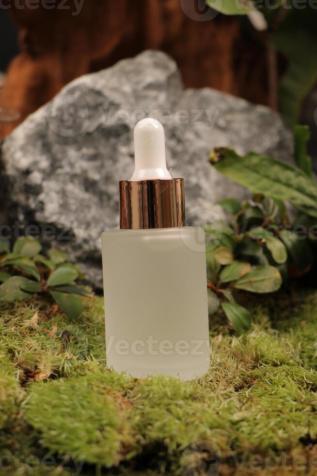 Frosted Dropper Bottle with Rose Gold Cap on Moss and Stone Background photo