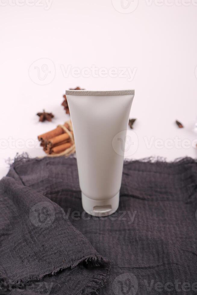 Natural Skincare Tube with Botanical Accents on Dark Fabric Background photo