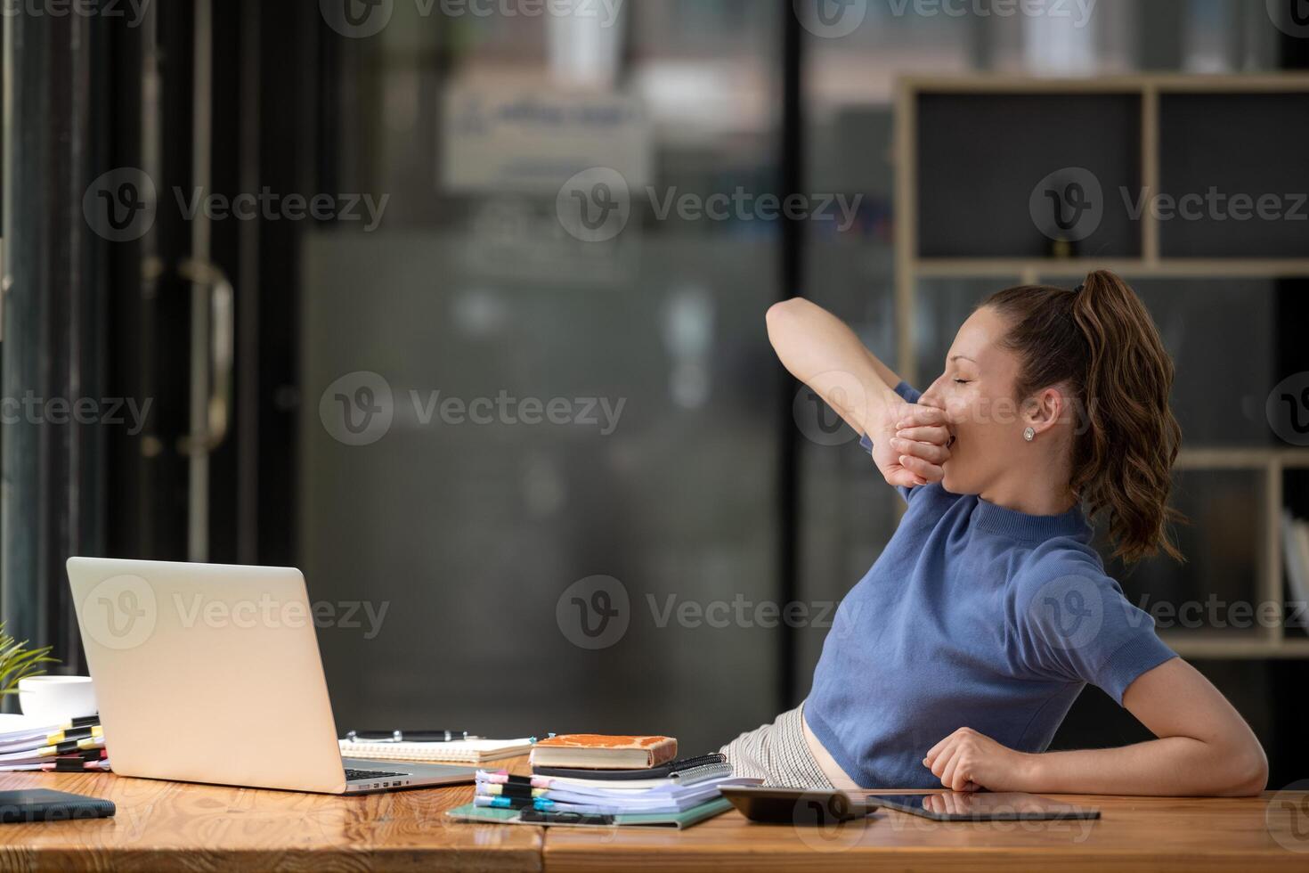 businesswoman yawning and stretching lazy while working with a laptop computer. Feeling bored and tired photo